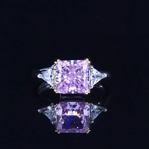 Macro view of a radiant cut pink gemstone ring with triangle side stones on reflective surface