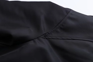Makroaufnahme der verstärkten Nähte auf dem schwarzen Nylon-Fliegerjackenstoff