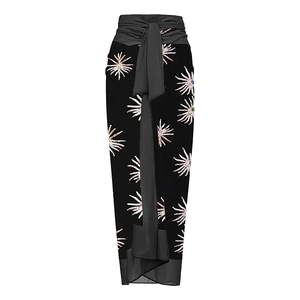 Detail of black wrap maxi skirt featuring white starburst print and tie waist