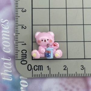 Detailed view of a pink resin bear charm holding a blue milk tea cup for DIY crafts