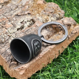 Close-up of retro lucky number 13 punk bell keychain resting on rustic cork and grass