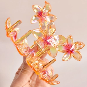 Detail showing an orange iridescent flower hair claw clip with a glossy finish