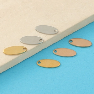Detailed view of six oval stainless steel jewelry tags in gold, silver, and rose gold