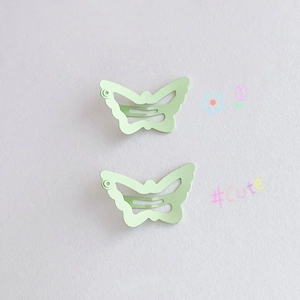 Close-up of two mint green butterfly hair clips with wavy snap metal design