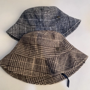 Close-up view of two vintage plaid wool bucket hats in black and brown patterns.