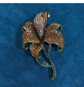 Detailed view of lily brooch with amber rhinestones and vintage gold finish on blue suede