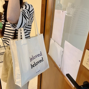 Détail de la broderie beloved sur le sac fourre-tout en toile porté par un mannequin