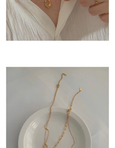 Detail view of gold teardrop pendant necklace and thin minimalist ring set on skin