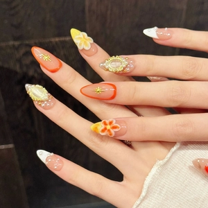 Almond press-on nails with embossed flowers, pearls, and cat eye stones in warm tones