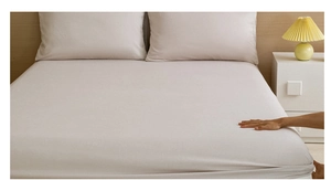 Close-up of elastic fitted sheet corner being pulled to show perfect mattress fit
