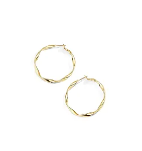 Macro view of gold hoop earrings featuring a twisted metal texture and polished finish