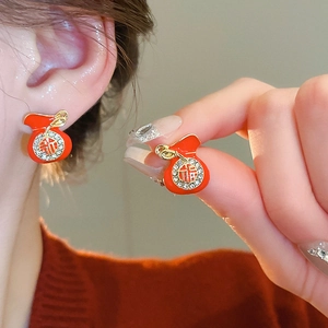 Macro view of red lucky bag stud earrings with gold trim and sparkling crystal details