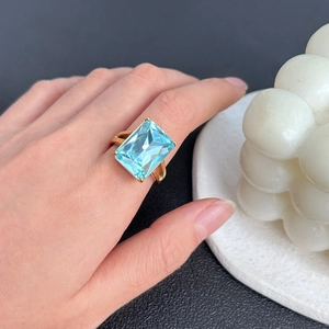 Elegante anello in titanio placcato oro 18K con una grande gemma azzurra taglio smeraldo