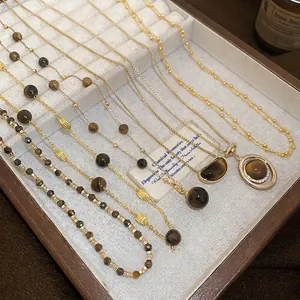 Elegant gold tiger eye stone pendant necklace set displayed in a wooden jewelry tray