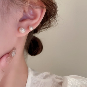 Close-up of elegant pearl stud earrings worn by a model in two different sizes
