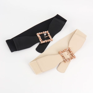 Detail of elastic belts in black and beige with sparkling gold rhinestone square buckles