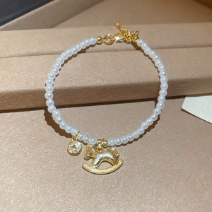 Détail d'un bracelet de perles avec un pendentif cheval à bascule doré élégant