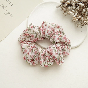 Detail of floral scrunchie with pink flowers on white chiffon fabric in soft lighting