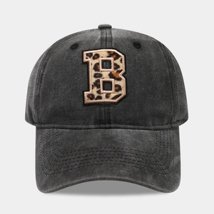 Detail of embroidered leopard print letter B on washed black denim baseball cap