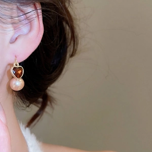 Élégantes boucles d'oreilles cœur en grenat et perle avec crochets dorés sur un mannequin