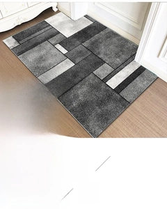 Detail view of a geometric gray rectangular doormat on a light wooden floor surface