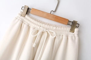 Close-up of cream knit sweatpants featuring an elastic waist and white drawstring details