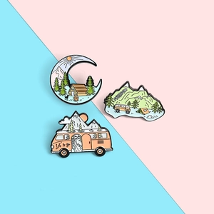 Detail of macaron-colored enamel outdoor pins featuring camper vans and mountain motifs