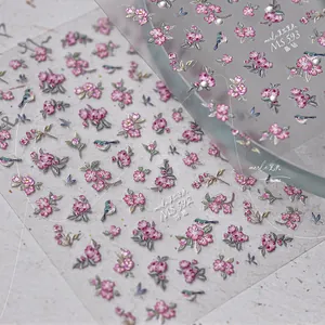 Macro detail of embossed pink floral and bird nail stickers with glitter finish