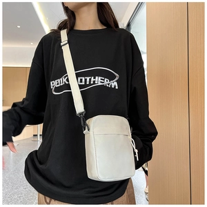 Side view of white minimalist nylon crossbody bag with adjustable strap worn by model
