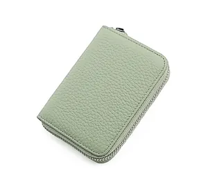 Dettaglio porta carte in pelle verde chiaro con trama a grana fine e cerniera in metallo
