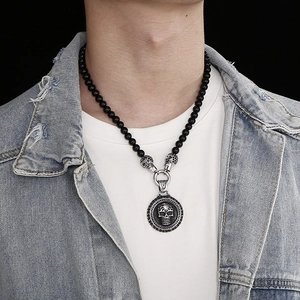 Close-up of model wearing black agate bead necklace with silver skull pendant on white tee