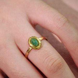 Detailed close-up of a gold stainless steel ring featuring an oval green natural stone