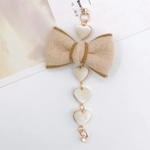 Detail of beige felt bow with white velvet hearts and golden chain DIY accessory