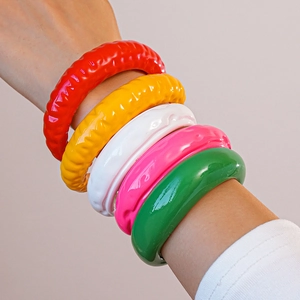 Dettaglio di bracciali in acrilico colorato con texture a onde e finitura lucida