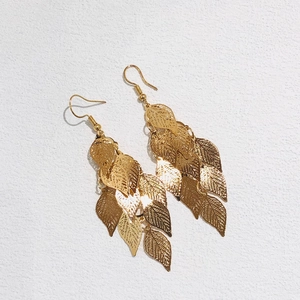 Detailed close-up of golden multi-layer leaf earrings with fine hollowed-out metal texture