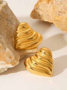 Macro view of 18k gold heart studs with textured stripes on natural stone