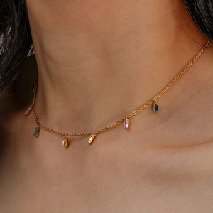 Close-up of gold chain necklace with colorful rectangular zircon pendants on model