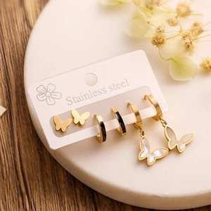 Detail of a stainless steel gold butterfly earring set on marble with floral accents