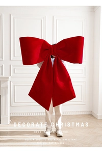 Detail of extra large red velvet Christmas bow held by person showing giant scale
