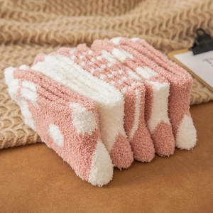 Pink and white coral fleece thermal socks stacked on a cozy blanket for winter warmth
