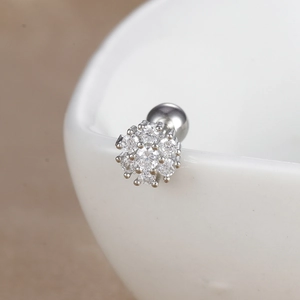 Vue macro d'un piercing fleur en argent avec zircons brillants sur céramique blanche