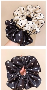Close-up of silk polka dot scrunchies in cream and black with pleated ruffled details