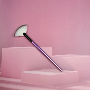 Dettaglio di un pennello a ventaglio viola con setole bicolore su sfondo rosa