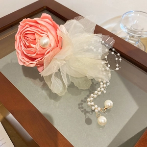 Detail of pink fabric rose hair clip with white pearls and delicate lace tassels
