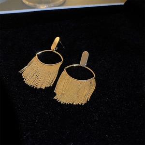 Macro shot of gold-plated oval tassel earrings on black velvet for a luxury look