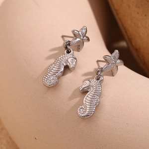 Detailed macro view of silver seahorse and starfish studs in polished stainless steel