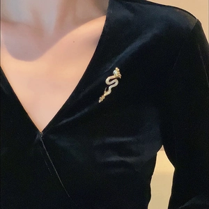 Detailed view of a gold-plated dragon brooch with cubic zirconia on black velvet