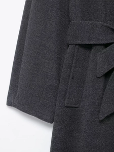 Detail of dark grey wool coat showing twill weave texture, cuff and belt design