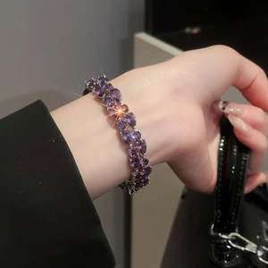 Close-up of luxury bracelet featuring pear-cut purple gemstones on female wrist