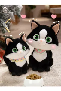 Two black and white plush cat dolls with big green eyes and knitted bibs on a soft rug